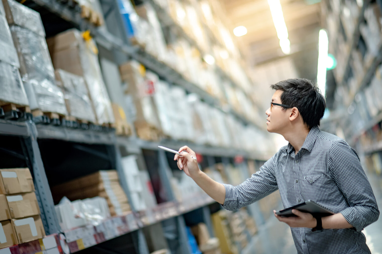 Young man in warehouse checking inventory on shelves.