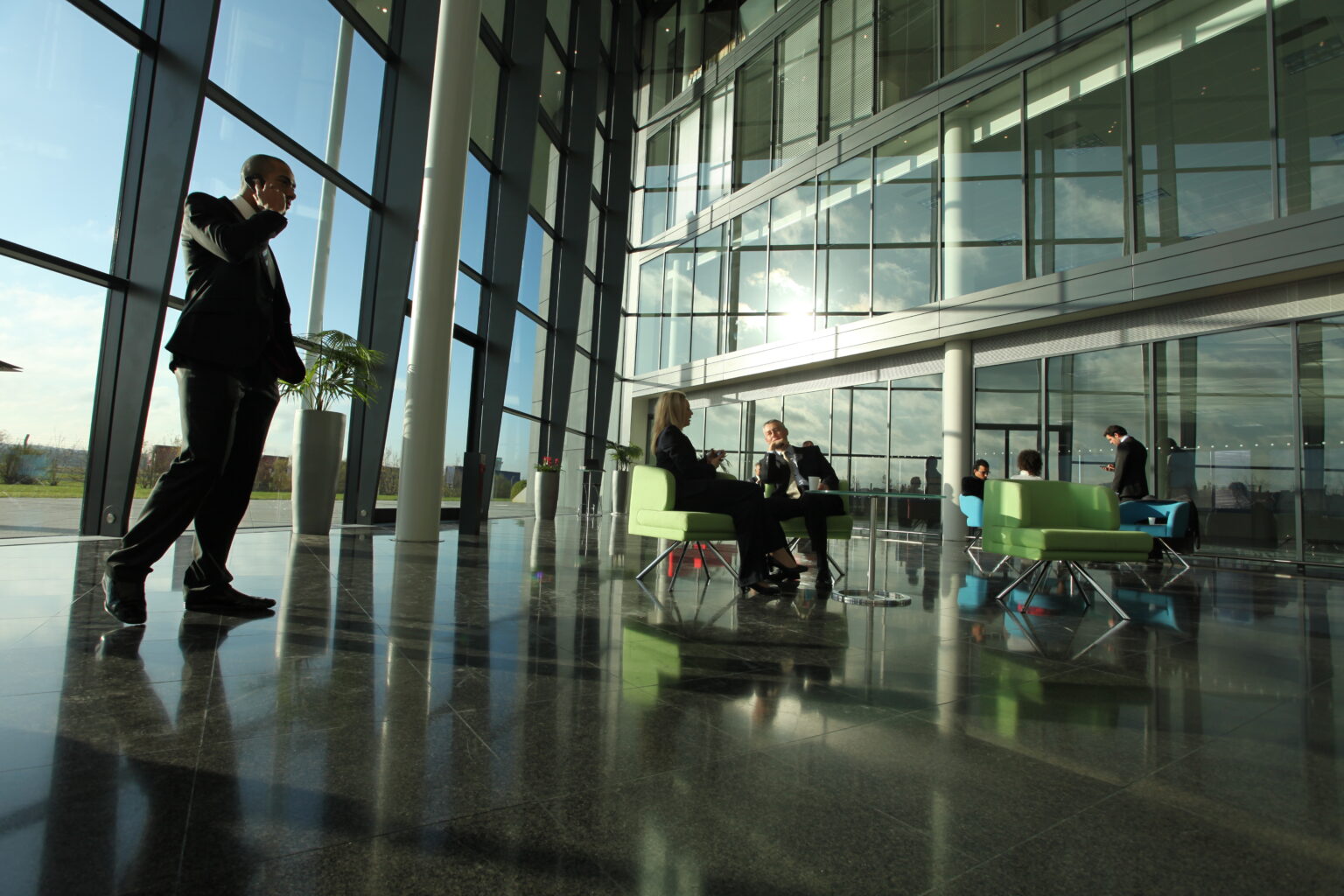 Businessman on phone walking through modern building lobby.