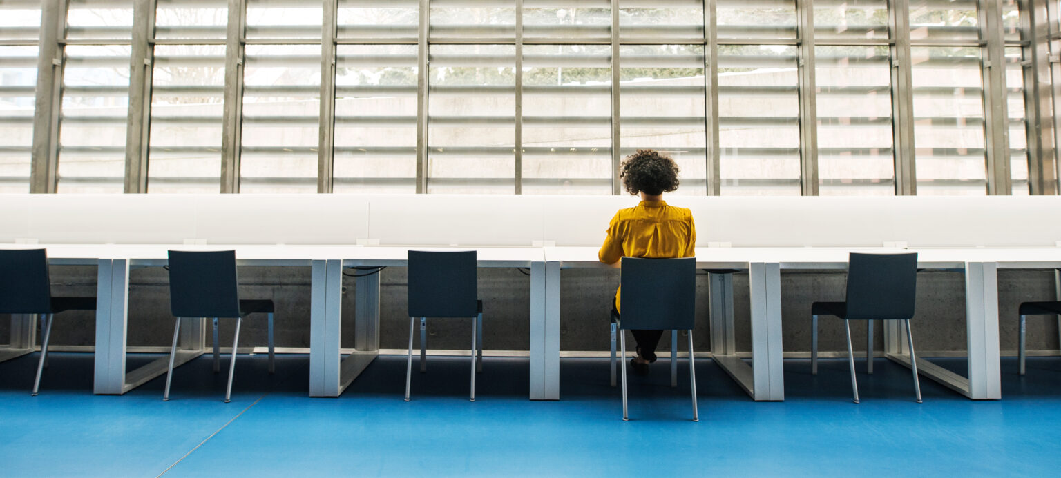 Artistic shot of a woman working at a bank of desks.