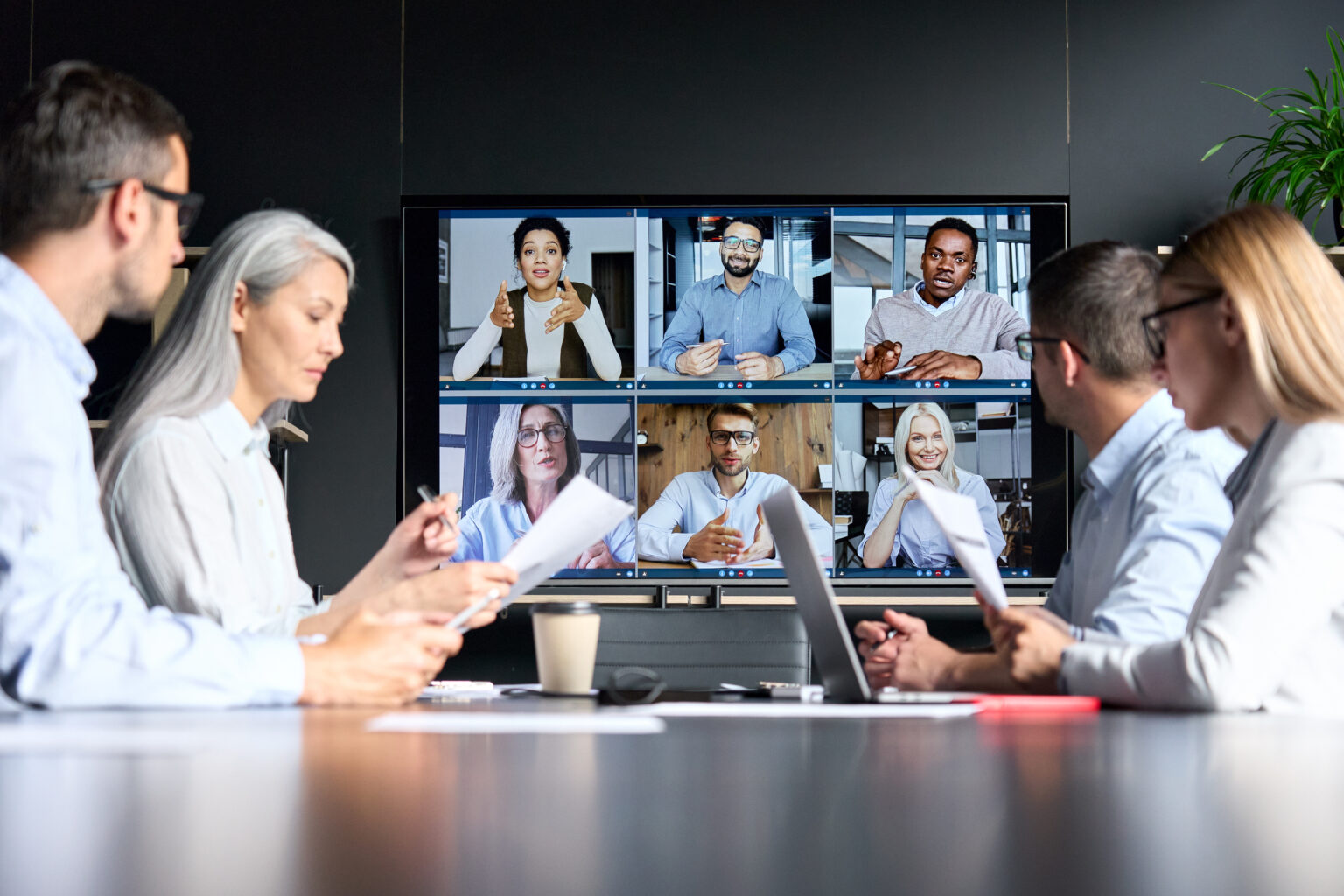 A conference room with remote worker's images on a conference screen.