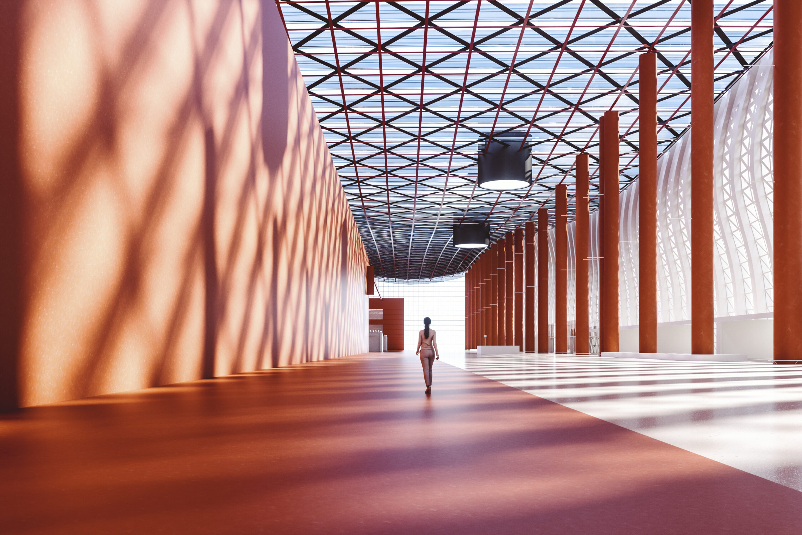 An artistic shot of a woman walking through an orange mezzanine area with long shadows on the wall.