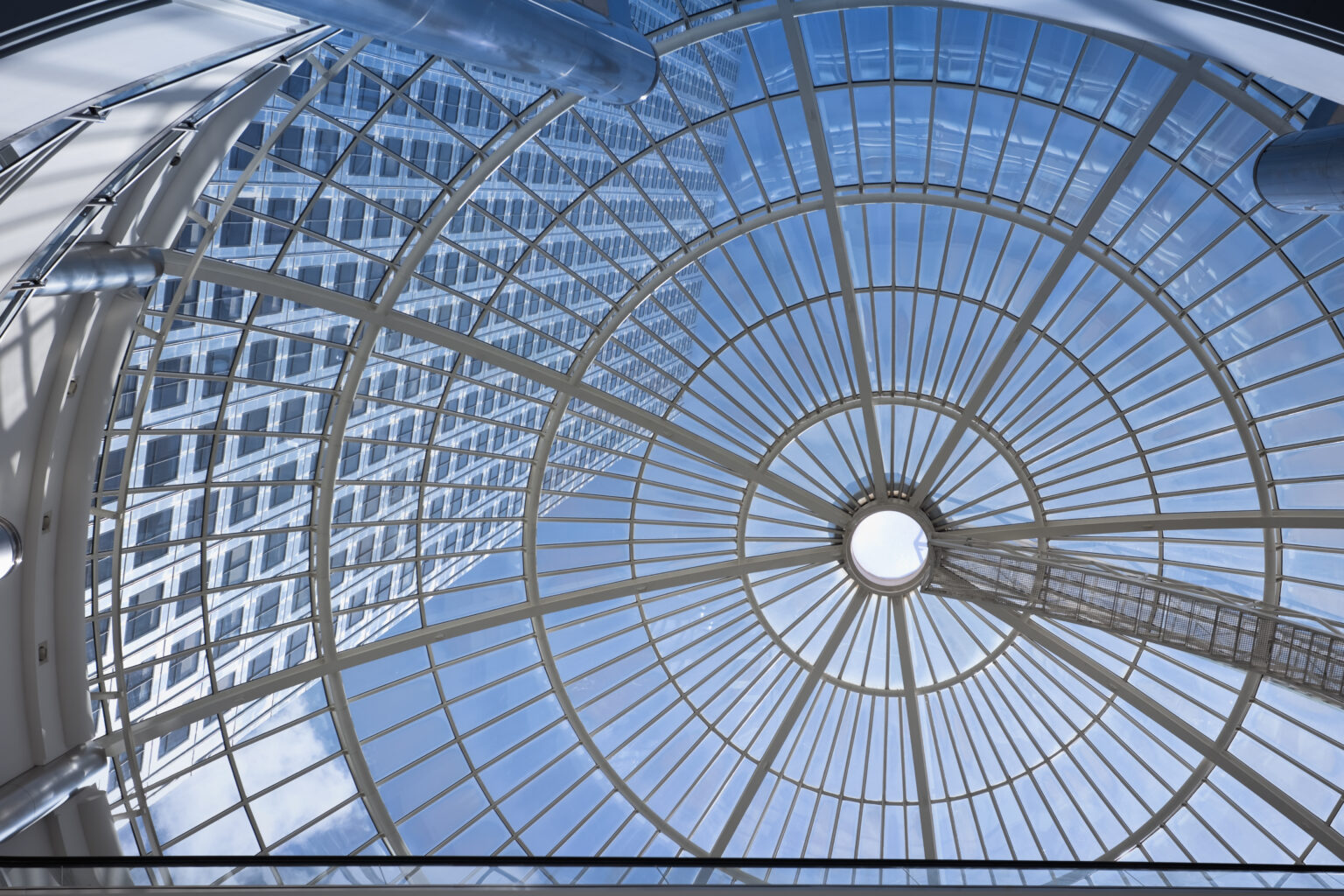 Skyward view of a glass atrium dome with circular gridwork.