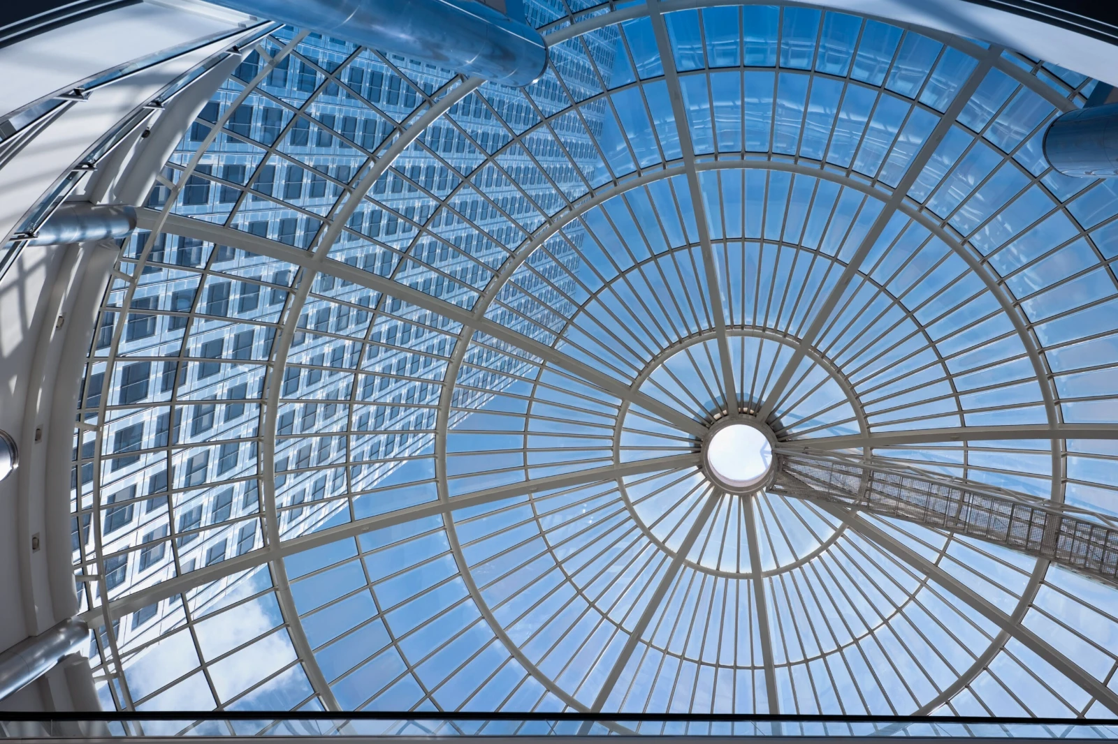 Skyward view of a glass atrium dome with circular gridwork.