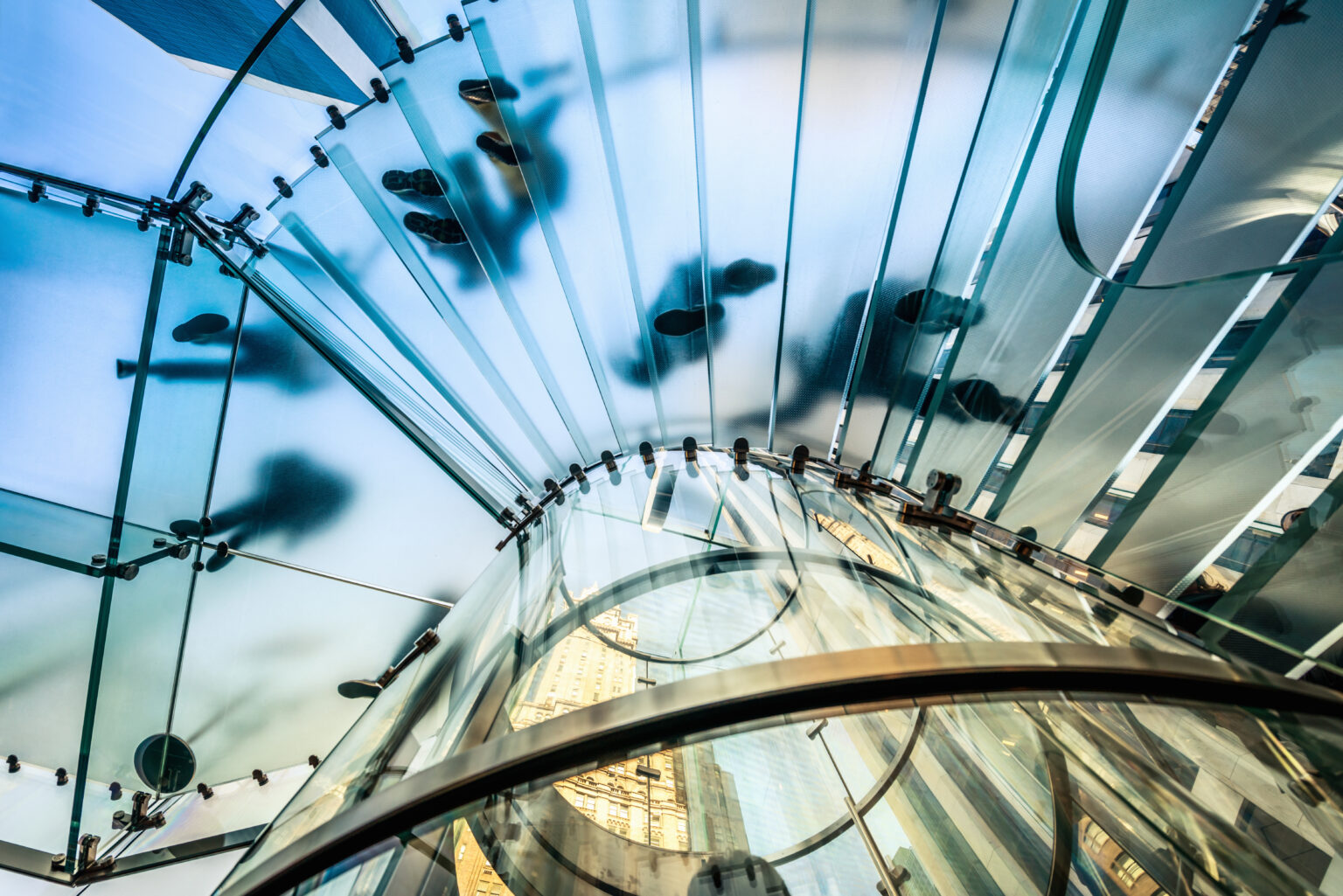 Upward view of a glass staircase with business people ascending.