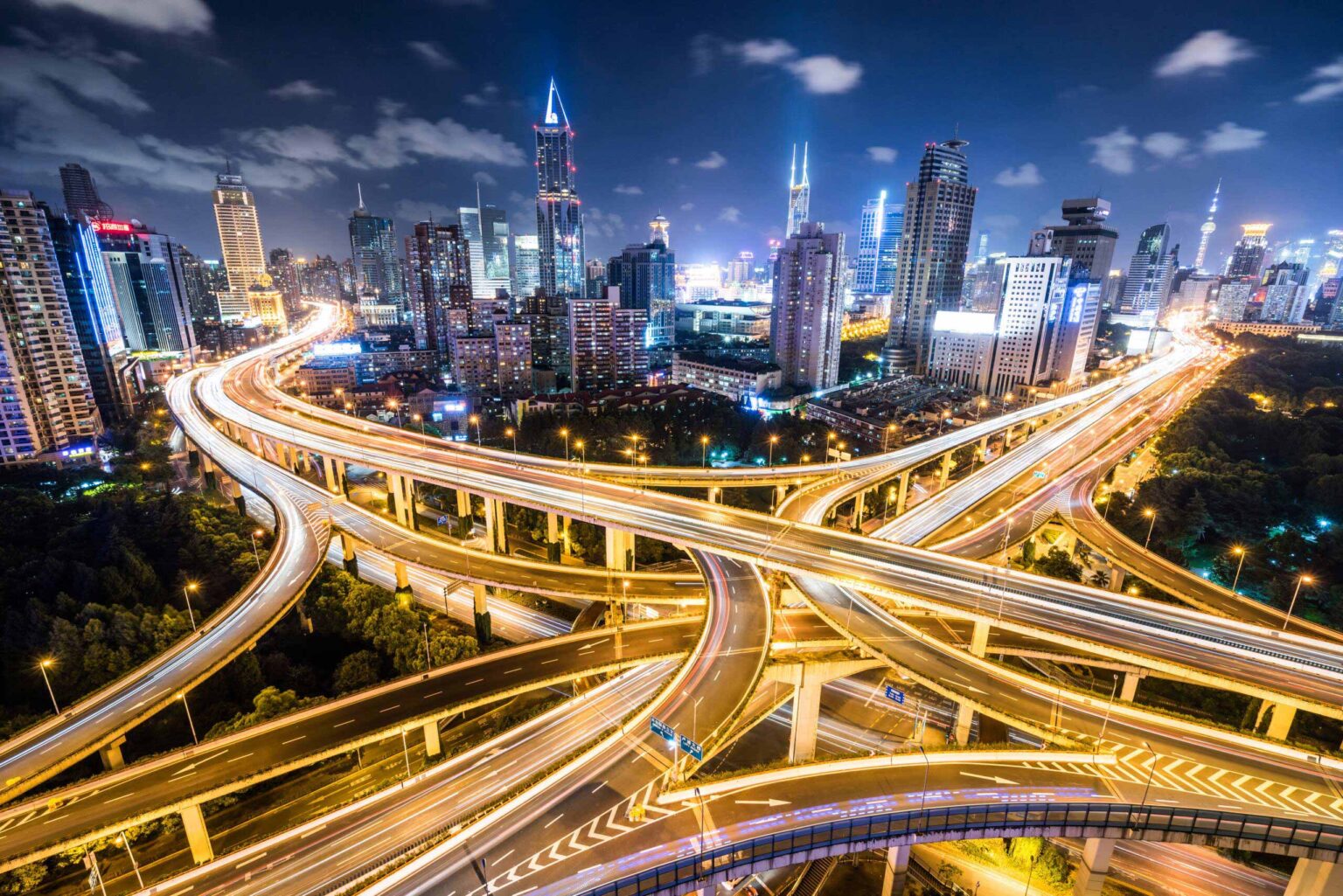 Night view of freeway stack with streaking car lights.