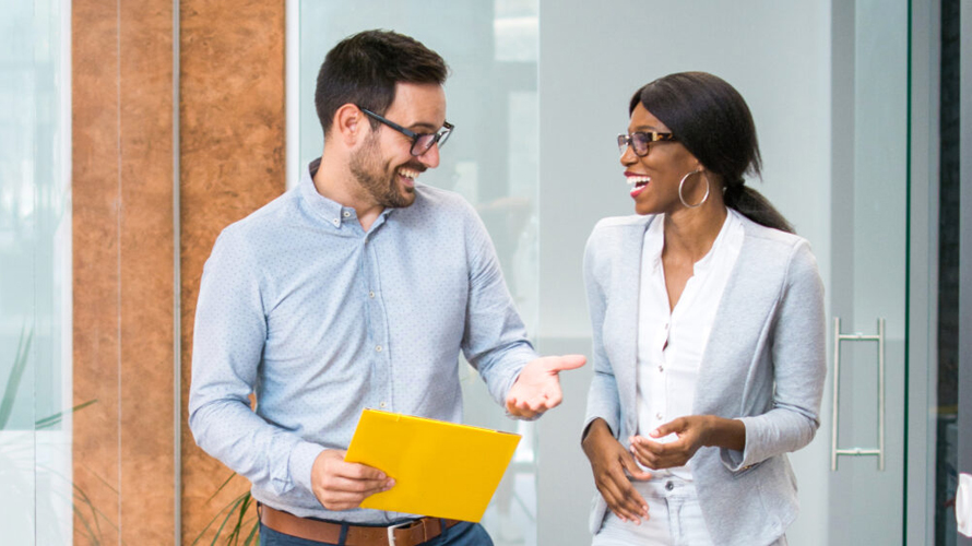 A businessman and businesswoman talking while walking through an office.